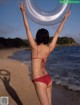 A woman in a red bikini holding an inflatable ring on the beach.