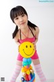 A young girl holding a smiley face balloon sculpture.