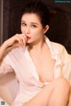 A woman in a white shirt sitting on a white chair.