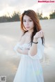 A woman in a white dress standing on a beach.