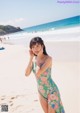 A woman in a floral dress standing on a beach.