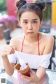 A woman sitting at a table eating an ice cream cone.