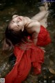 A woman in a red dress laying in the water.