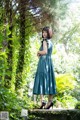 A woman in a blue dress standing in the woods.