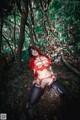 A woman in a red outfit is sitting in the woods.