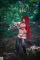 A woman dressed as a red riding hood in the woods.