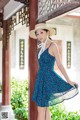 A woman in a blue dress and a straw hat posing for a picture.