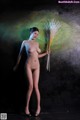 A naked woman holding a bunch of wheat in her hand.