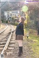 A woman in a school uniform standing on a train track.