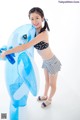 A young girl in a bikini standing next to an inflatable dolphin.
