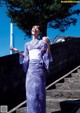 A woman in a purple kimono standing on some steps.