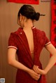 A woman in a red cheongsam with her back to the camera.