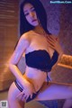 A woman in a black lingerie posing for the camera.