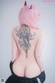 A woman with pink hair and a tattoo on her back.