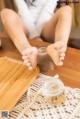 A woman sitting on a wooden table with her feet on a tray.