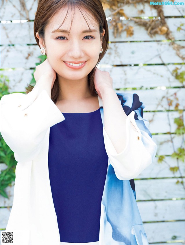 A woman in a blue top and white jacket posing for a picture.