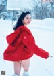 A woman in a red jacket is standing in the snow.