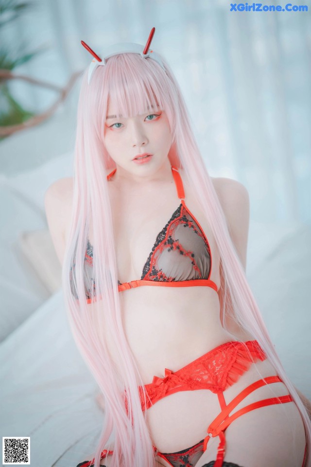 A woman with long pink hair wearing a red lingerie.
