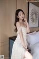 A woman in a white dress sitting on a bed.