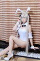 A woman in a bunny costume sitting on a bench.