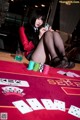 A woman sitting at a poker table holding a card.