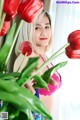 A woman holding a bunch of red tulips in her hand.