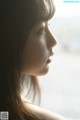 A woman looking out of a window at the ocean.