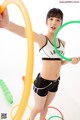 A woman in a sports bra top and shorts holding a hula hoop.