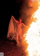 A woman standing in front of a fire in the dark.