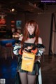 A woman in a black and orange outfit holding a box of coffee.