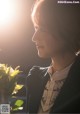 A woman in a black jacket holding a white rose.