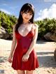 A woman in a red dress posing on a beach.