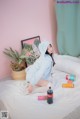 A woman sitting on a bed with a bottle of coke.