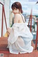 A woman in a white dress sitting on a red railing.